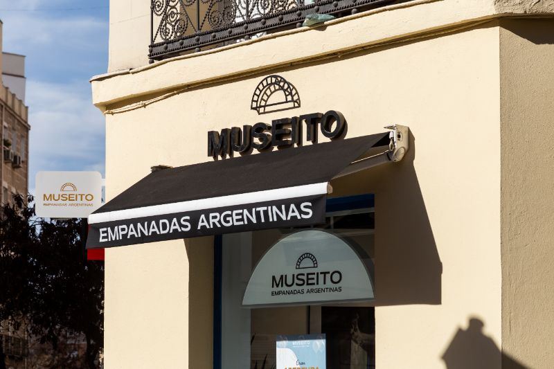Nombre Museito sobre un toldo en una fachada clara