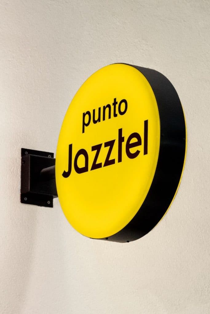 Banderola circular amarilla con el nombre punto Jazztel y soporte negro