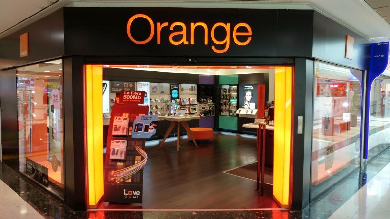 Frente de una tienda con rótulo Orange y acceso abierto