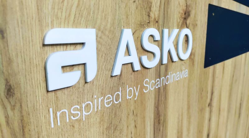 Logotipo y letras Asko y lema Inspired by Scandinavia sobre una pared de madera