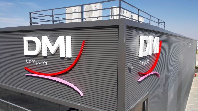 Letras DMI Computer y símbolo de color en dos caras de una fachada