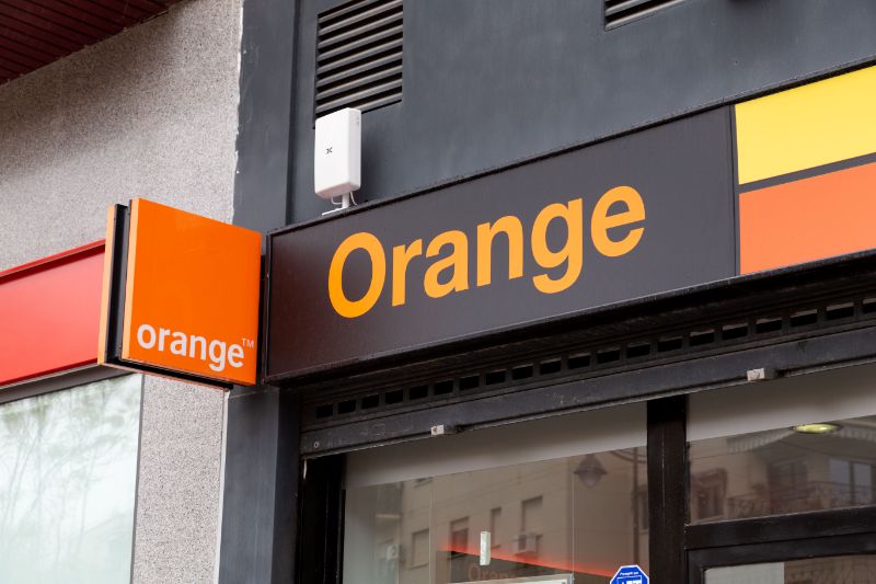 Rótulo Orange y banderola sobre la entrada de una tienda