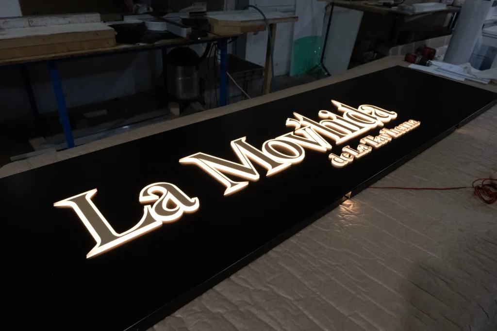 Rótulo iluminado de La Mov’hida sobre una mesa de taller